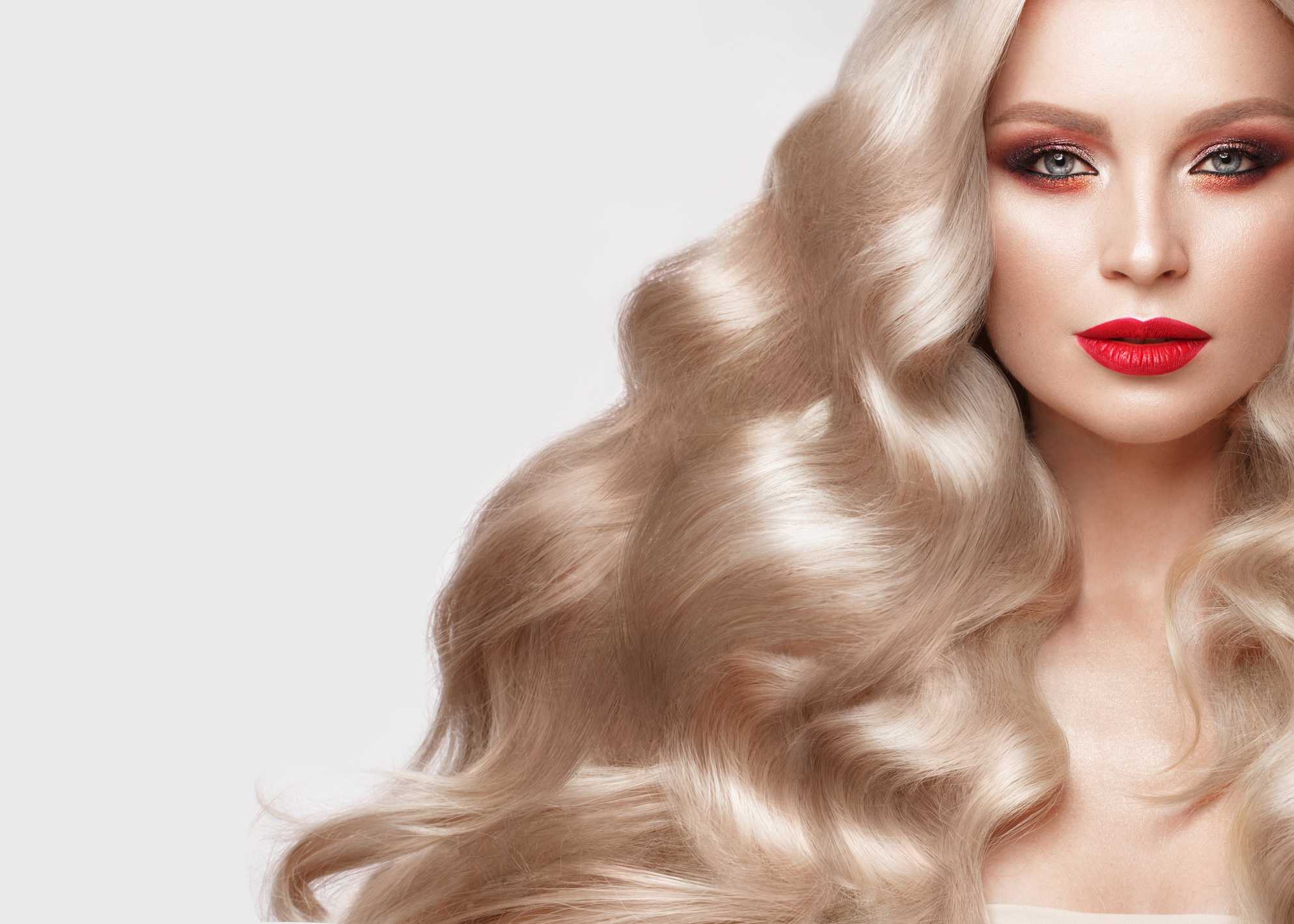 Beautiful Blonde in a Hollywood Manner with Curls, Natural Makeup and Red Lips. Beauty Face and Hair.